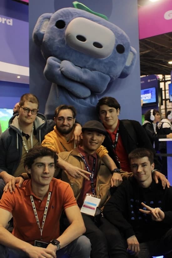 Des membres de l'agence FCA posant pour une photo avec une grande mascotte du personnage Wumpus de Discord en arrière-plan.